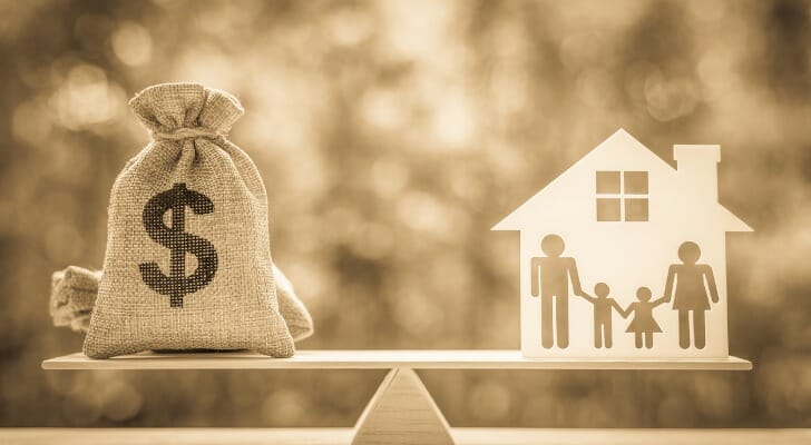 Money bag on a see-saw opposite a house with a family.