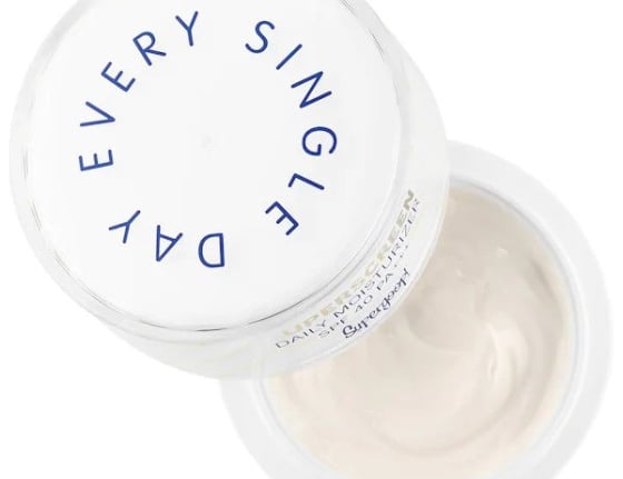 Open jar of eye cream with white lid labeled Supergoop