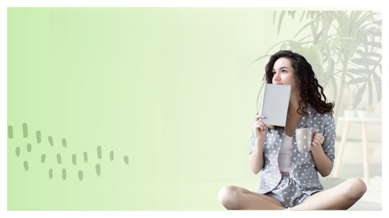 Young woman in pajamas holding a book and coffee mug in a relaxing green room.