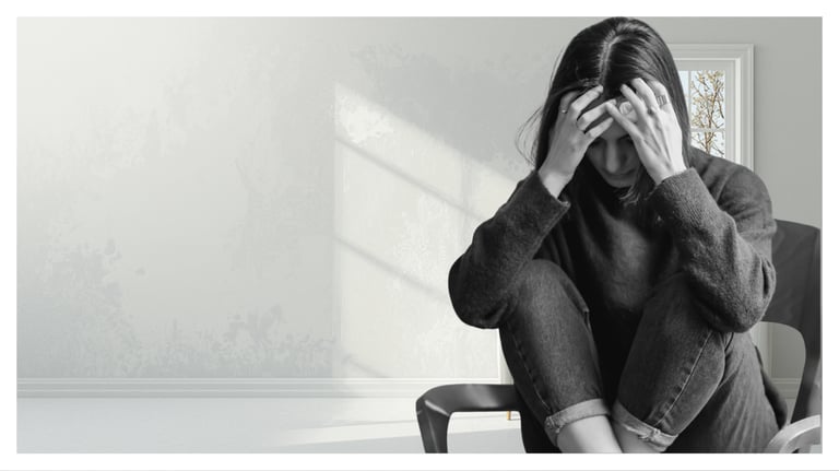 A stressed woman sits in a chair holding her head, illustrating anxiety, depression, and mental health struggles.