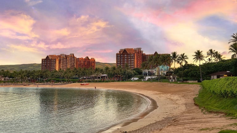 Disney's Aulani Resort towers above the tropical sands of a Hawaiian beachfront.