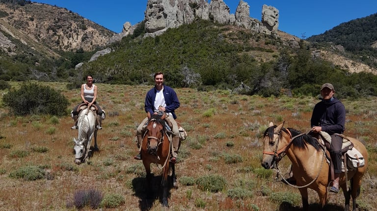 People on horseback riding in a mountainous landscape.