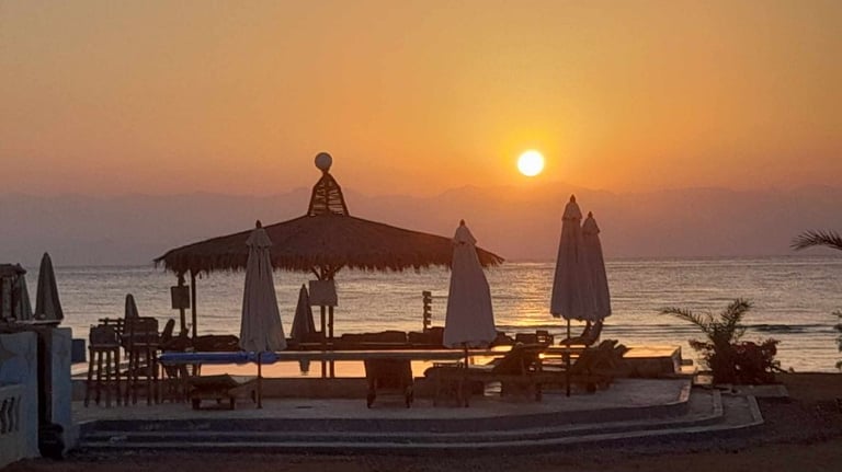 Soft sunrise view over the beachfront swimming pool and traditional arisha at Bedouin Star camp