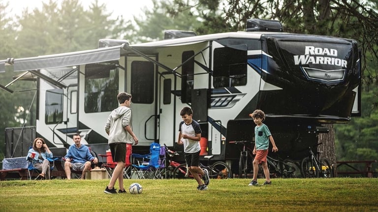 a group of people playing soccer in a field near an RV