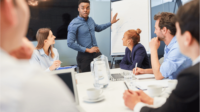 a man in a suit and tie is standing in front of a white boardroom