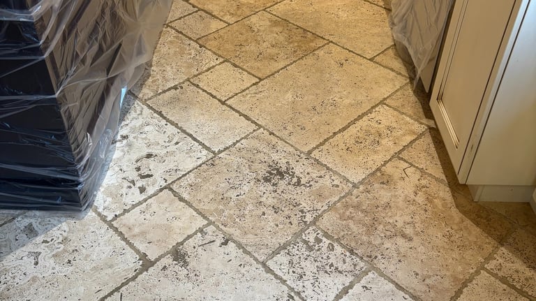 Dirty travertine tile floor in kitchen before professional cleaning