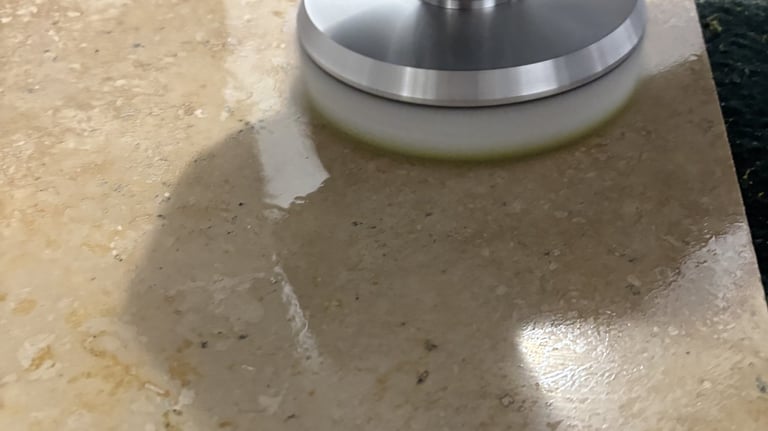 Technician in black glove polishing travertine stone floor surface