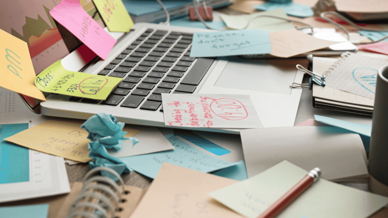 a laptop computer sitting on a messy desk with sticky notes