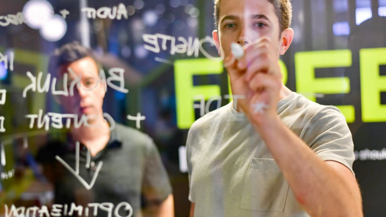 a man holding a marker in front of a transparent glass writing board - Swrill