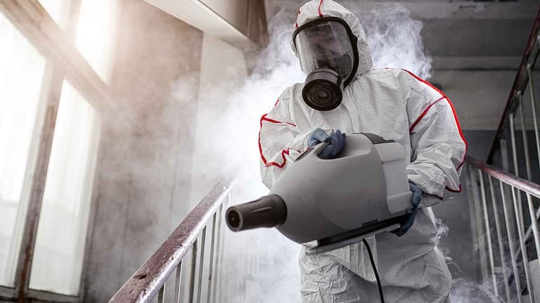 a man in a white suit and a gas mask disinfecting a stair railing