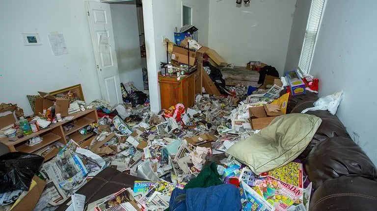a messy hoarders living room with a couch and a couch