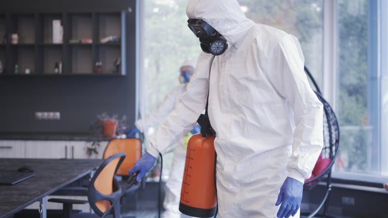 a man in a white hazmat suit and a canister with disinfectant