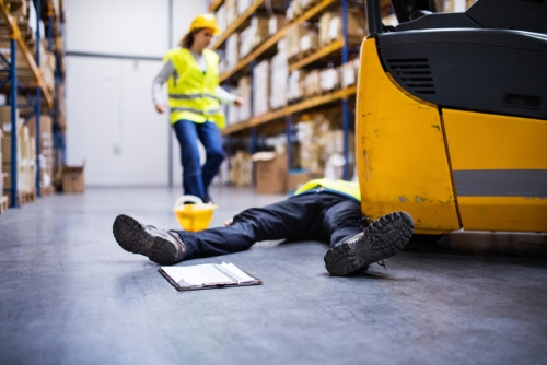 a man laying on the floor in a warehouse with a woman coming to his aid