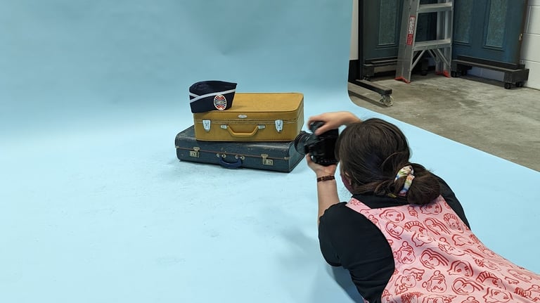Laura photographs a set of vintage suitcases on a blue backdrop for Closet Mod in an Adelaide