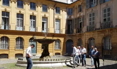 place avec une fontaine à Aix-en-Provence avec des personnes regardant l'architecture