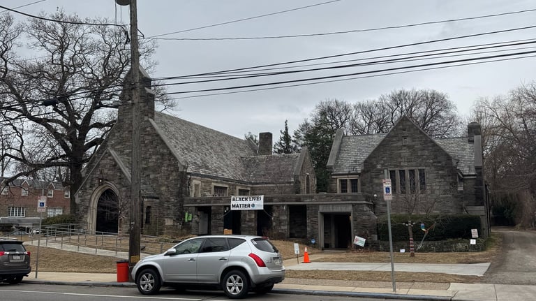 Picture of church building including slight street view with two parked cars.