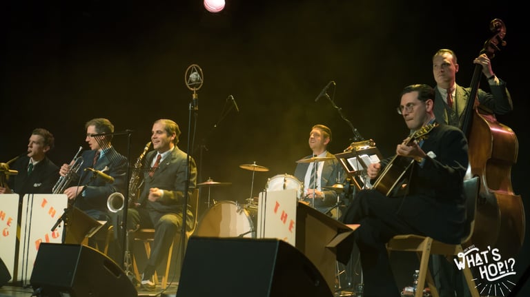 A vintage-style swing jazz band performing live on stage with brass instruments, drums, and double bass.