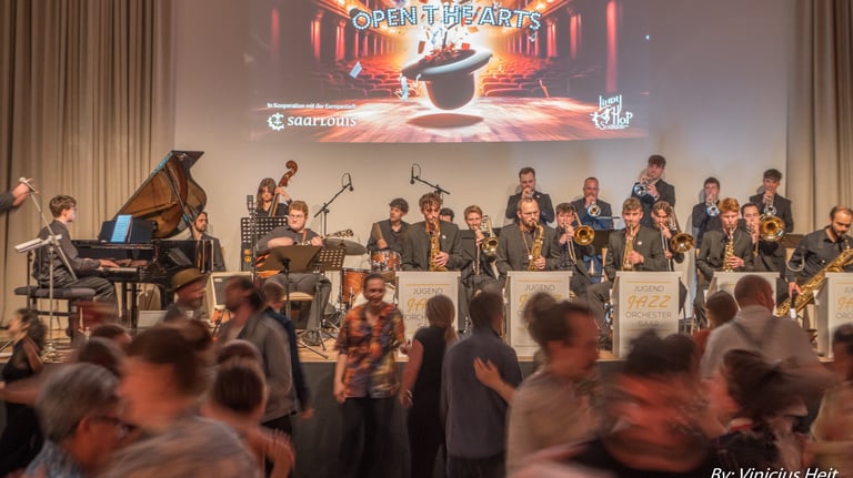 A live big band jazz orchestra performing on stage while people dance at a swing dance event.