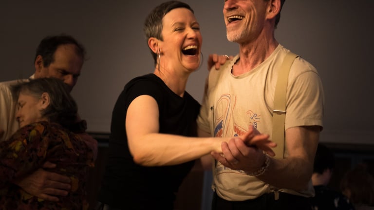A happy man and woman laughing while ballroom dancing at a social swing dance event.