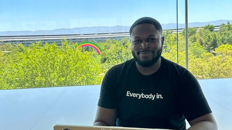 A young professional smiles and wears a black shirt that says, "Everybody in."