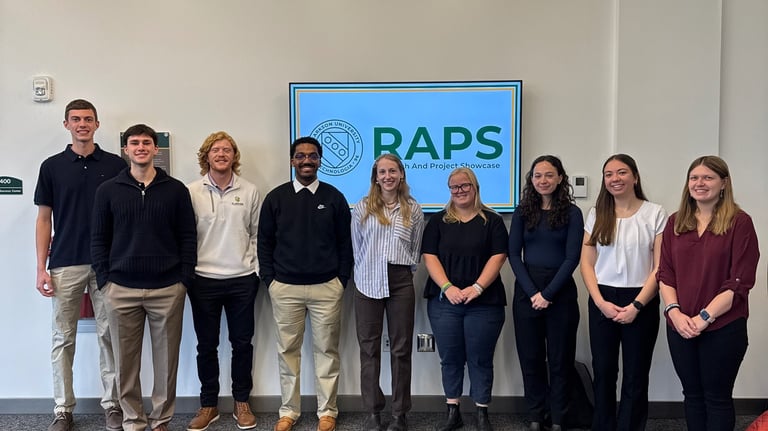 A group of young professionals in business attire stand together and pose for a photo.