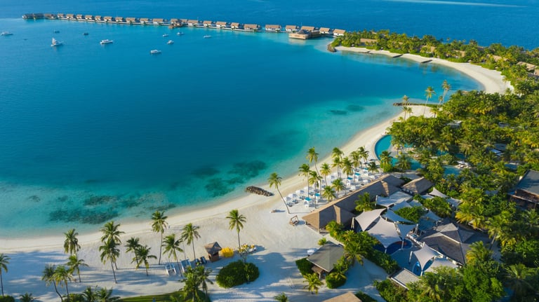 a beach with a boat in the water, waldorf astoria maldives