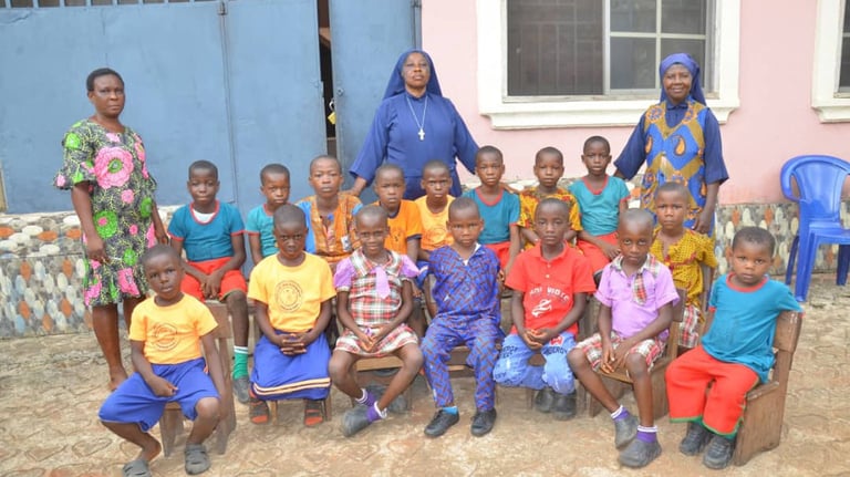 A group of African school children and teachers posing for a photo at a local community school.