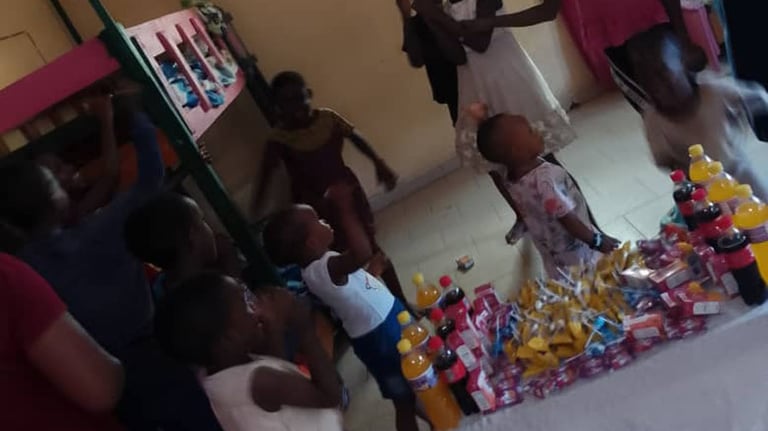 Children celebrating at a community event with snacks and juice bottles on a table in a room.