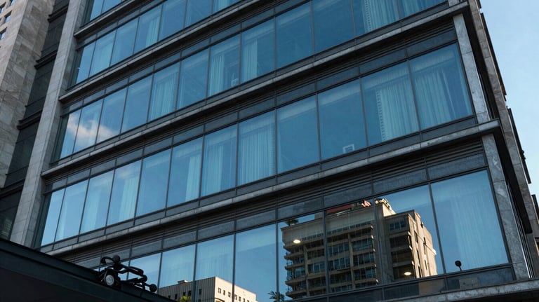 An architectural detail of a modern Brazilian law firm facade with glass windows reflecting a clear blue sky, evoking transparency and modernism.