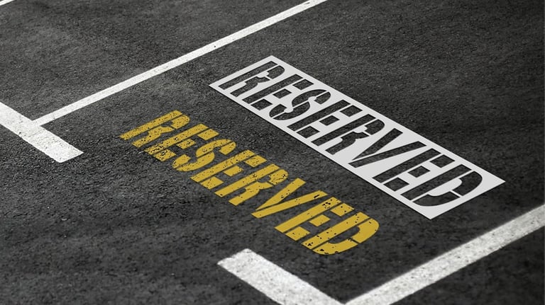 Reserved parking spaces with white and yellow stenciled text on dark asphalt pavement.