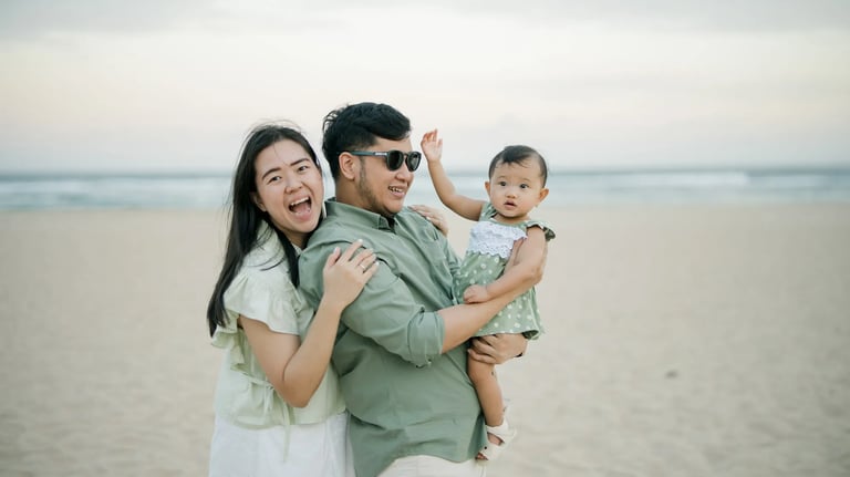 Parents holding their daughter during a natural family photography session on the beach in Bali.