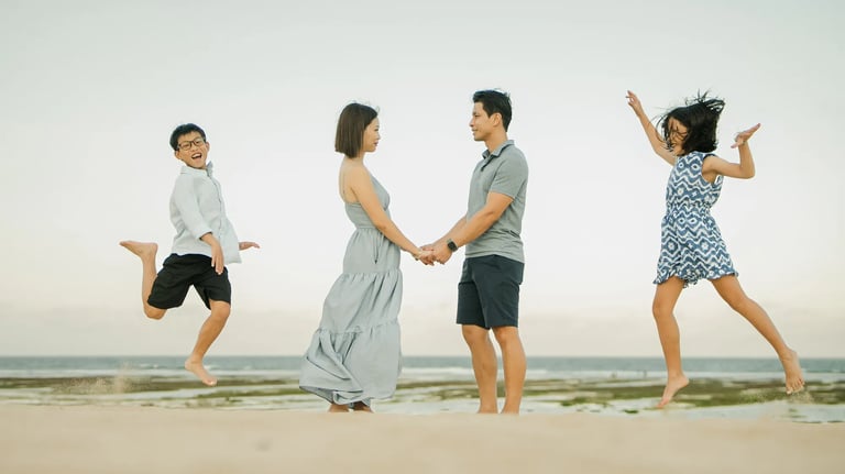 Family holding hands and walking together during a beach photography session at The Ritz-Carlton Bali.