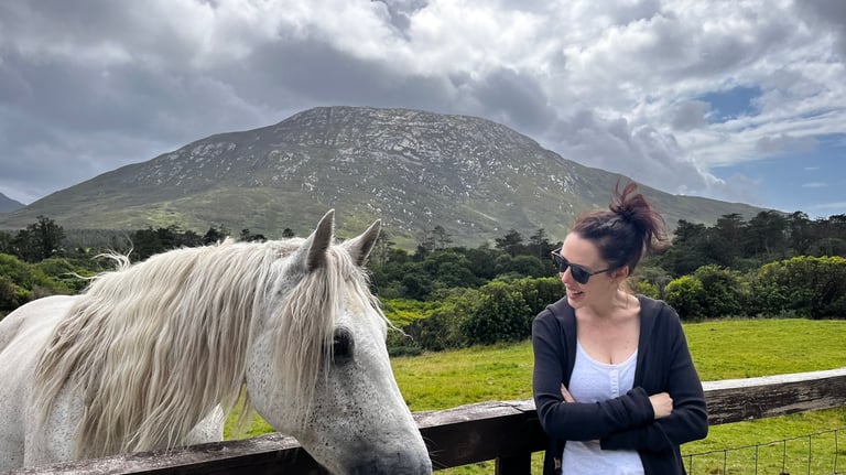 a woman standing next to a horse in a field