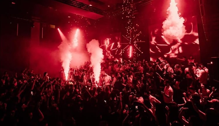 a crowd of people standing around a stage with red lights