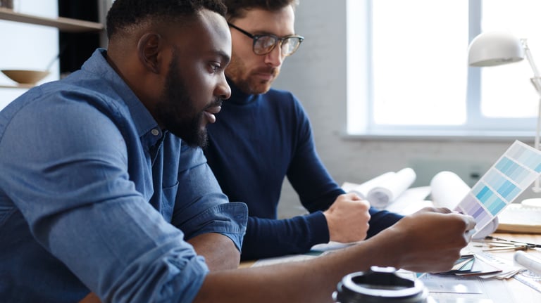 two men sitting at a desk with a laptop