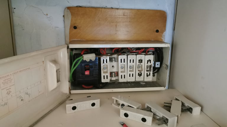 An old residential fuse box with ceramic wire fuses removed for electrical maintenance.