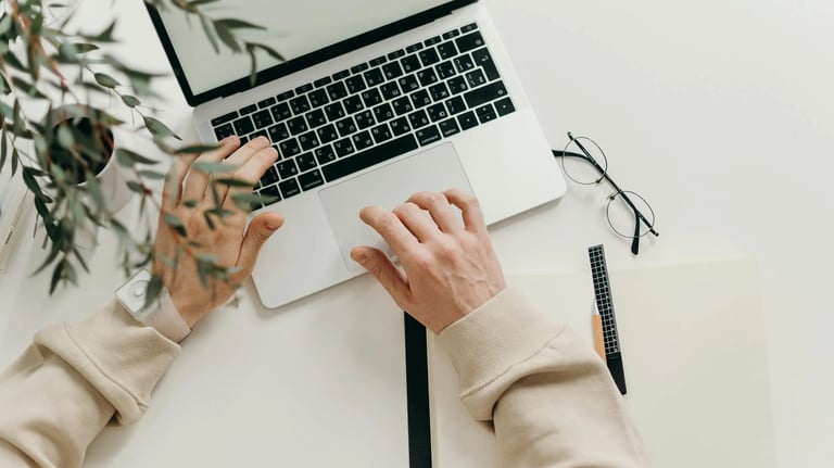 a person's hands typing on a laptop computer