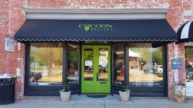 The Cocoon Gallery storefront features lime green doors and a black awning over artisan craft displays.