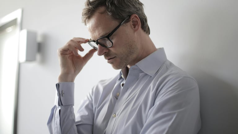 a man in a shirt and glasses is holding a cell phone