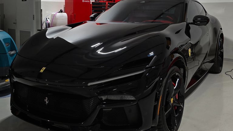 A deep black Ferrari Purosangue after receiving a full front Paint Protection Film (PPF) installatio