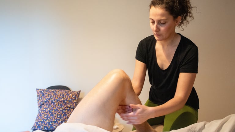 Masseuse qui masse le mollet sur jambe repliée