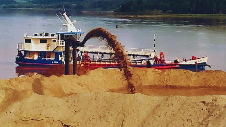 a boat is being loaded with sand and a crane