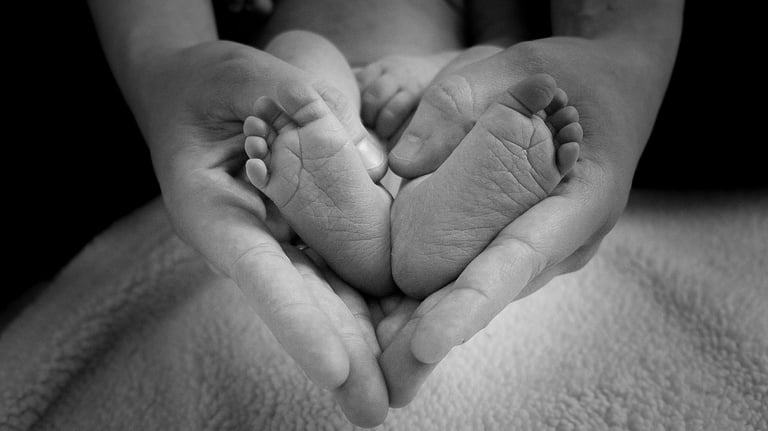 Manos de una madre y pies de un bebé con forma de corazón