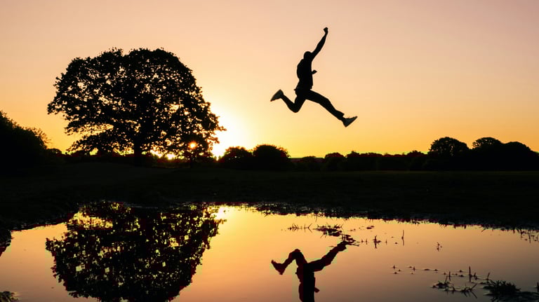 Mann springt vor Sonnenuntergang als Zeichen für das befreite Gefühl nach der Hypnose.