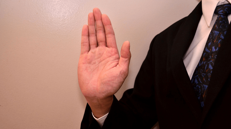a man in a suit and tie is holding his hand up to the camera