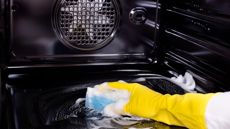 avra cleaning services person cleaning a stove top oven with a sponge pad
