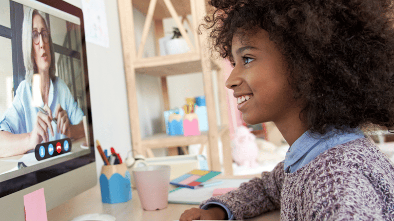 Girl smiling at teacher on screen in an online lesson