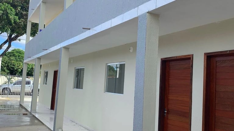 Modern multi-story apartment building with white tile walkways and dark wood doors.