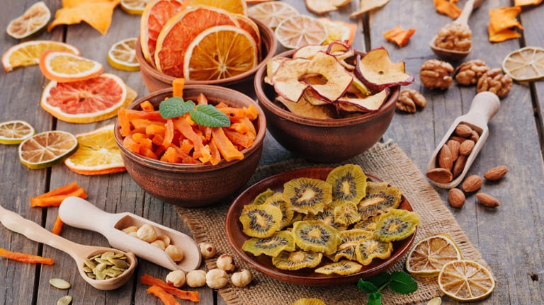 Bowls con trozos de frutas deshidratadas: kiwi, limón, mango, pomelo, naranja. Algunos frutos secos.