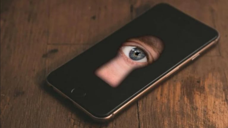 Celular con imagen de un ojo asomándose  por la mirilla de una puerta